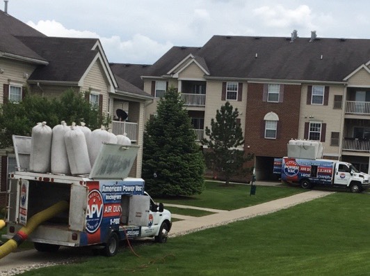 Two Power Vac Duct Cleaning trucks in action at an apartment complex