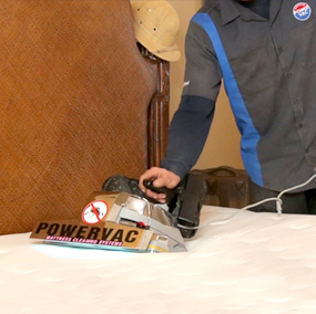 A Power Vac technician uses a mattress cleaning tool.